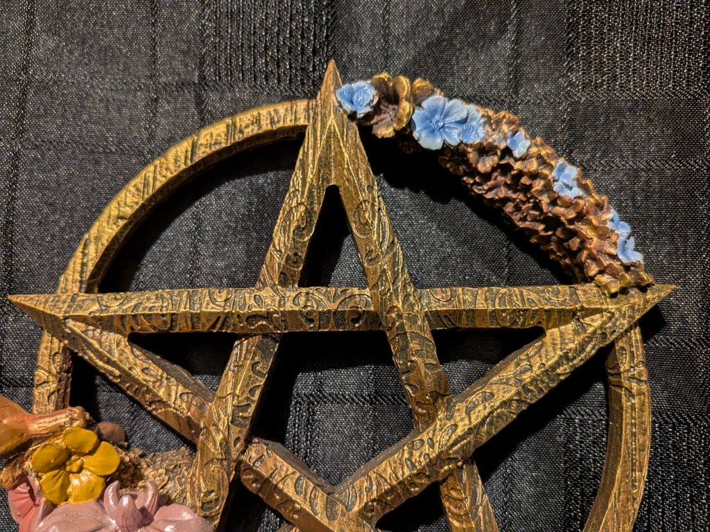 Ostara gold pentagram close-up with blue flowers